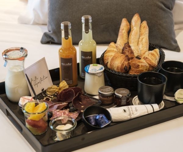 Petit-déjeuner varié d'exception servi sur un plateau, avec des produits bio et du terroir, composés d'ingrédients de qualité, livré directement en chambre pour une expérience gastronomique unique et un début de journée parfait.